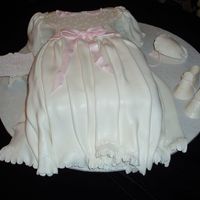 Christening Gown, Booties And Bonnett fondant christening gown with pearls on bodice, gumpaste booties and gumpaste bonnett.