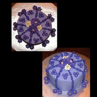 Purple_Cake_003_Copy.jpg This is my first fondant covered cake. I did it in class. Two tones of purple fondant, with royal icing flowers. If it happens to look blue...
