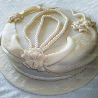White Pearls 12" round chocolate cake with chocolate filling, covered in fondant. The pearls are made of fondant. The drapes and flowers are made...