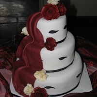 Burgandy Roses vanilla sponge cake covered in fondant with fondant drape. Gumpaste roses