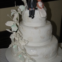 Cascading Orchids sponge cake covered in forndant with gumpaste orchids and bride and groom.Brush embroidery on cake dusted with lusterdust