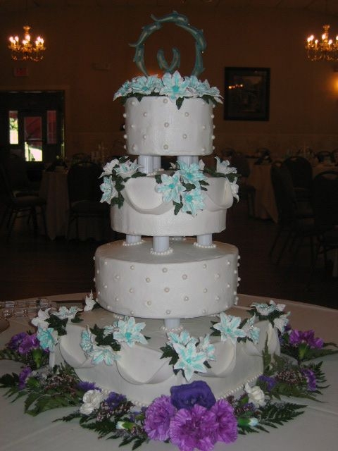 First 12 inch square base, 10, 8 and 6 inch round tiers. Icing is all buttercream with pearl bead accents and royal icing lillies. Swags are made...