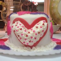 L-O-V-E Oval shaped 6 layer chcoclate cake with buttercream icing covered with chocolate ganache beneth white fondant. The hearts are made of...