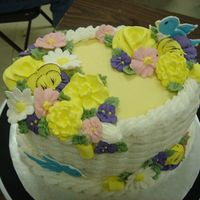 Wilton Course Ii Class Graduation Class Oval cake 4", basket weave in buttercream, with royal icing mixed spring flowers. Birds are color flow.