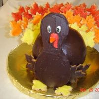 Turkey Cake, Cookie Feathers Vanilla cake made in sports ball pan. BC icing. Cookies cut with mid-size maple leaf cutter. Cookies pasted on candy sticks with candy...