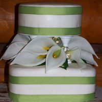Cala Lily Wedding Cake This cake is covered with fondant and a green ribbon around to match wedding colors. Lilies are fake and arrangment is made to take off and...