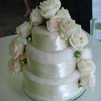 Ivory And Creme Wedding Cake Round 3 tiered wedding cake with ivory icing, creme ribbon and creme roses
