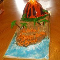 Volcano Surprise 60th birthday cake. The Volcano is covered in chocolate fondant, the sand is brown sugar, and the palm trees are made from...