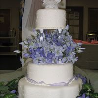Lilac Anniversay 3 Tier Cake. Pillar & Stacked Construction. 2 Rounds and 1 Petal. Fondant over Buttercream w/white scrollwork.