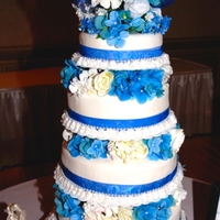 Blue & White Wedding Cake 4 tier wedding cake with fondant, blue ribbon with blue & white silk flowers using Tall-tier cake stand.