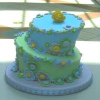 Floral Delight 6" and 8" topsy turvy tiered cake in shades of blue, violet, green and yellow decorated with fondant fantasy flowers