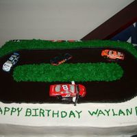 Race Track i made this for sons 11th birthday. The cake is a 9x13 covered is buttercream bc grass and chocolate MMF race track