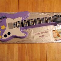 Hannah Montana Guitar 2-layer cake iced in BC with fondant decorations. Main part of guitar was carved from a 12x18. Cake board is 14x36!!!