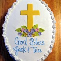 Christening Cake 2-layer oval white cake with Buttercream Icing, fondant cross, flowers and leaves, silver dragees.