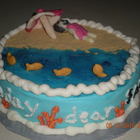 Beach Cake Vanilla cake with buttercream frosting. Girl and umbrella are candy clay. Sand in graham cracker crumbs. Water is piping gel colored blue...