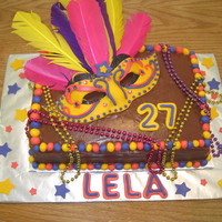 Mardi Gras Birthday Chocolate fudge cake with chocolate fudge buttercream icing. Fondant mask laid on a cardboard mask with feathers. Colorful Mardis gras...