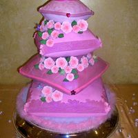 Pillow Cake A four tiered princes pillow cake in different shades of pink and lace design . Hand made sugar roses as well as hand made fondant tiara...