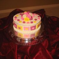 Squares And Roses 71/2 inch oval. White chocolate cake with lemon mousse filling and BC icing. Fondant accents.