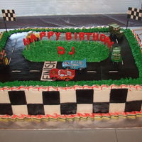 Cars Birthday Cake Yellow cake with buttercream frosting and half fresh strawberries and bananas and other is whipping filling. Blsck squares and racing track...