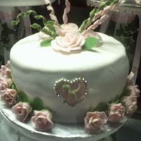 Quinceanos This is a white cake cover with fondant and has a border of fondant roses and a pink heart with initial on center of heart . The top is a...