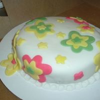 Flower Cake THIS IS AN ALMOND FLAVORED SPONGE CAKE COVERED WITH WHITE ROLLED FONDANT AND DECORATED WITH ROLLED FONDANT FLOWERS