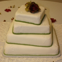4 Teir Square Wedding Cake Vanilla cake with whipped icing and covered in white fondant. Green buttercream icing around bases white buttercream swirls.