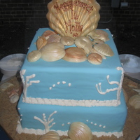 Sweet Sixteen Down By The Shore Cake is covered in fondant. Shells were made with white chocolate and dusted with luster dust. Sand is brown sugar