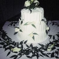 Cake1 My first wedding cake. Three stacked tiers coated and finished with white buttercream with fresh white spray roses and calla lilies.
