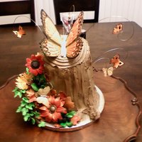 Tree Stump Cake With Gumpaste Flowers Tree stump cake with hand made gumpaste flowers. Large butterfly pastilliage. Smaller ones gumpaste. A few feather butterflies added.