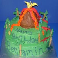 Volcano And Dinosaur Cake Cake I made for a neighbor. It is a 2 tier cake with a volcano made with a giant cake ball. Trees are royal icing and pretzel sticks.