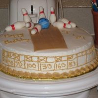 Bowling Cake A cake with a bowling lane on it and the ball knocking the pins down.