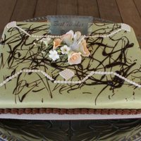 Sage Geometric Cake is decorated with sage buttercream icing and chocolate buttercream trim; fondant accents, a splash of ganache and a keepsake laminated...