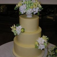 Wedding Cake For A Friend Three round tiers covered with pale yellow white chocolate, and decoratedwith gumpaste flowers including hydrangea, ranunculus, freesia,...