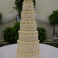 Roses And Glitz Seven tiered almond pound cake , iced in buttercream and covered in ivory fondant. Layers embellished in crystal chain and round crystal...