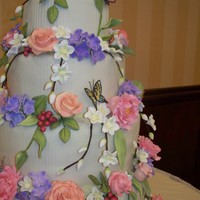 Floral Cake This cake features gumpaste and fondant peonies, roses, berries, apple blossoms and butterflies, all handmade and handpainted. The tiers...