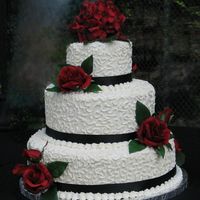 Burgundy Rose White chocolate buttercream frosting with cornelli lace. Black ribbon and silk flowers selected by bride.