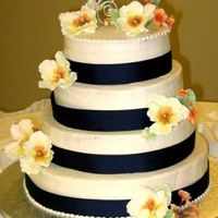 Wedding Cake - Blue With Peonies This was a buttercream cake with satin navy blue ribbon, gumpaste peonies in orange and yellow and orange primroses for coordinating design...
