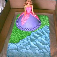Princess By A Pond Doll pan for skirt. All b.c. icing. Used paper towel method on the skirt. The grass and water wrapped around the side of the cake.