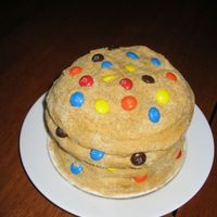 M & M Cookie Cake The cake is a 6" white cake with chocolate chip cookie dough filling, covered in buttercream with crushed vanilla wafers for texture....