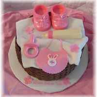 Baby Girl Items In Basket... Everything is edible. Fondant bib, blanket and flowers. Chocolate booties, bottle and pacifier. Thanks for looking! :)