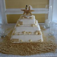 Beach Theme Wedding Cake White cake, vanilla pudding and coconut filling, fondant icing, white chocolate sea shells, crushed cookies as sand.