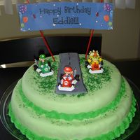Mario Kart Birthday Cake This is a double chocolate cake covered in fondant and a buttercream border. The road is also made of fondant wth green sprinkles as grass...