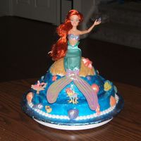 Little Mermaid Cake 12" round topped with original wonder pan, frosted in buttercream. Used glitter gel for water. Molded chocolate shells covered with...