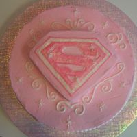 Supergirl Cake 12" round and 8" square set on diagonal with one corner cut off. Iced w/buttercream and covered in pearl luster dust.