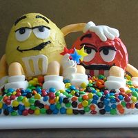 M&m Birthday Cake Red and Yellow have a chocolate cake center and covered with buttercream mixed with almond extract. They have fondant accents. They sit on...