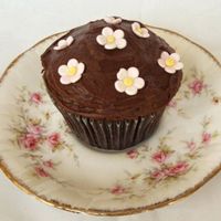 Blossom Chocolate Cupcake Dense Chocolate cupcake with fudge icing and different sized gumpaste blossoms.