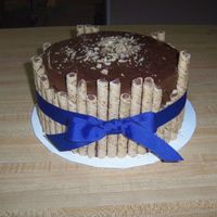 Chocolate Hazelnut Pirouette Cake chocolate cake w/Nutrella filling and icing. Hazelnut flavored pirouette around. Blue ribbon tied.