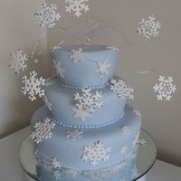 Blue Snowflake Cake Covered baby blue sugarpaste. Placed on table mirror rather than a cake board.Shaped cakes. Pastillage snowflakes.Snowflakes on wires made...