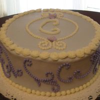 Monogram Cake A monogram cake for a going-away party for a co-worker. Usedscroll press along the sides. Royal icing violets on top. Tip 2 beads.