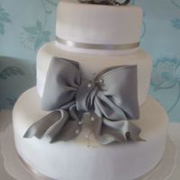 Contemporary Simple Wedding Cake Customer wanted a simple cake, but one that made a statement. Bow at front & on top modelled freehand and finished with sprays of...
